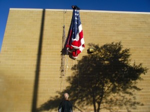 Volunteers haul the large flag up the side of the Mesquite Recreation Center.  The flag will continue to adorn the wall for the entire week as part of the 1000 Flags over Mesquite. Sponsored by the Exchange Club of Mesquite, 1000 Flags are flying for the tenth year in Mesquite honoring veterans past and present. Photo by Teri Nehrenz.